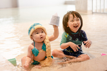 Two Kids in swimming pool. Children swim indoors.Child during vacation in a hotel.Little girl playing on a model beach.Having fun in swimming pool,Summer and vacation,Asian Family concept.