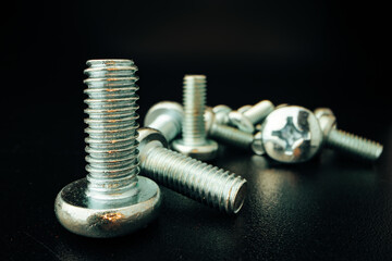 Metal screws and nuts on black background