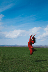 person in red suit jumping in the green field of grass