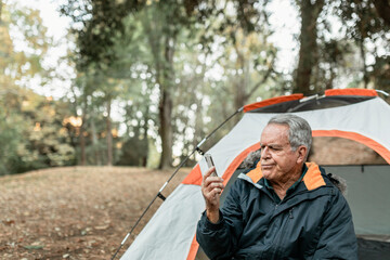 Elderly man searching for internet connection in the forest