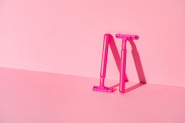Pink disposable razors on pink background, copy space