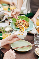 Close-up image of housewife putting portion of delicious seafood salad in bowl of guest at dinner