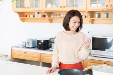 キッチンでスマホを見る女性