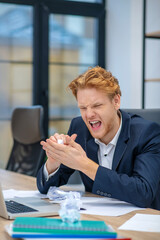 Naklejka premium Nervous young man clumping paper in hands