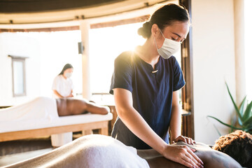Spa massage therapist with face mask working in the new normal