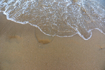 Sea surf, waves rolls on a sandy beach