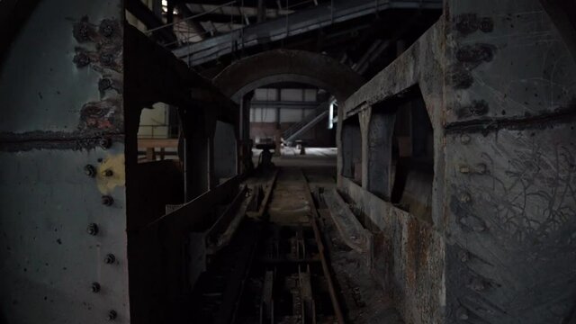 Walking through an old coal wagon turn around machine on rails of old abandoned coal factory plant. spooky creepy hall