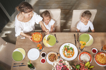 Woman serving family vegetarian table to children. Top view