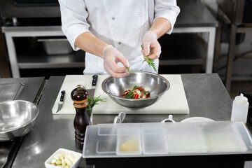 Beautiful man chef preparing dish with shrimps at table in kitchen