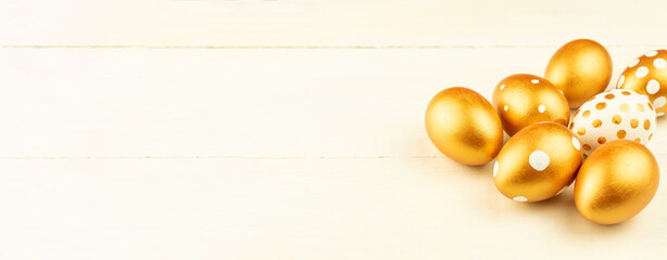 Easter festive decoration.Close up of easter eggs colored with golden paint on wooden background. Various dotted designs. Banner