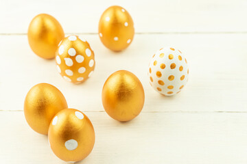Easter festive decoration.Close up of easter eggs colored with golden paint on wooden background. Various dotted designs