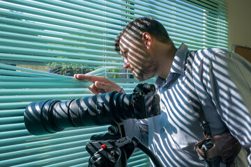 Detective of police look through blinds of window