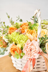 Small flower shop and Flowers delivery. Flower arrangement in Wicker basket. Beautiful bouquet of mixed flowers on wooden table. Handsome fresh bouquet.