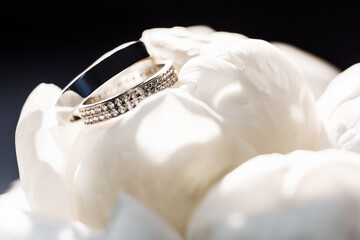 white gold wedding rings lie on peonies. wedding details. ring with precious stones. wedding day.