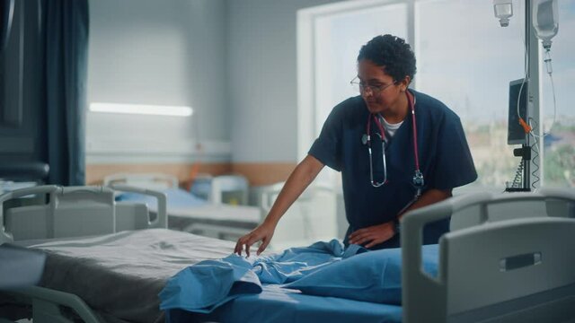 Hospital Ward: Beautiful, Professional Latin Black Nurse Working, Doing Bed, Cleaning Room After Happy Healthy Patients Recover and are Discharged Under Treatment of the Best Doctors. Sunny Room