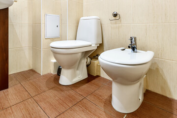 Fototapeta na wymiar White ceramic toilet and bidet in apartment bathroom