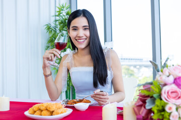 Obraz na płótnie Canvas Valentine's day concept, Asian young girl sitting at a table food with wine glasses and bouquet of red and pink roses wine and waiting for her man at in the restaurant background