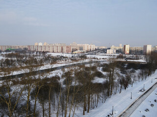Obraz premium Urban winter landscape from above. Multi-storey buildings and trees in the city park are visible.