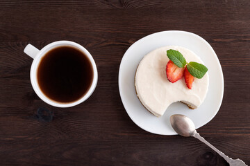 Cake, teaspoon and cup of coffee on dark wooden background. Dessert in cafe. Top view