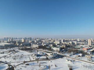 Obraz premium Urban winter landscape from above. Multi-storey buildings and trees in the city park are visible.