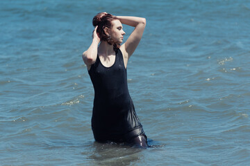 Young woman in black dress enjoys sea.