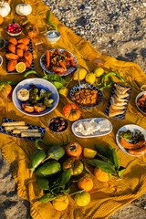 Beach picnic with various Mediterranean dishes and autumn fruits