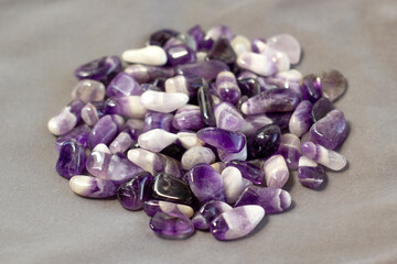 Set of various amethyst natural mineral stones and gemstones on grey linen background partial...