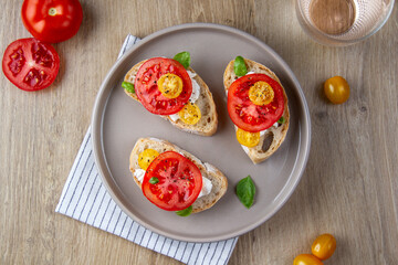 Bruschettes with curd cheese and tomatoes on a plate.