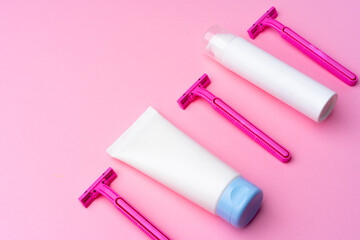 Shaving gel and disposable shaver on pink background top view