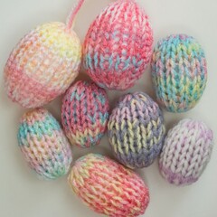Easter eggs decoration in pastel spring colors. Pink blue green yellow colorful yarn texture. Shallow depth of focus, light background. Crafts and arts, homemade crochet figures, hobby activity.