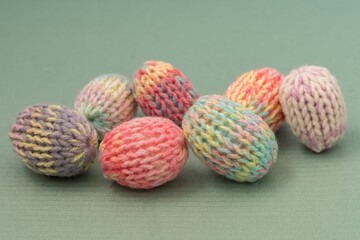 Easter eggs decoration in pastel spring colors. Pink blue green yellow colorful yarn texture. Shallow depth of focus, light background. Crafts and arts, homemade crochet figures, hobby activity.
