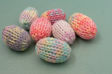 Easter eggs decoration in pastel spring colors. Pink blue green yellow colorful yarn texture. Shallow depth of focus, light background. Crafts and arts, homemade crochet figures, hobby activity.