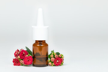 Nasal spray bottle of medicine with red flowers on gray background, allergy