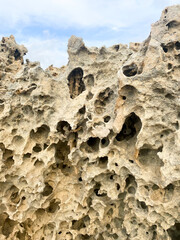 Sand with holes on the seashore. Sandy rocks on the beach of Mediterranean sea. Rough surface background.