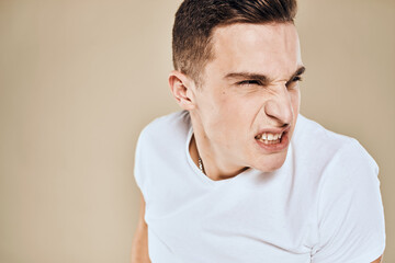 Man with displeased facial expression emotions white t-shirt gestures with hands beige background