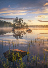 Scenic nature landscape with mood fog and beautiful sunrise at early summer morning in lakeside Finland - 410073730