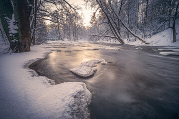Scenic winter landscape with flowing river and morning light in Finland. Snowy trees. - 410074178