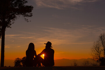 Fototapeta na wymiar Young couple enjoying the sunset in the mountain