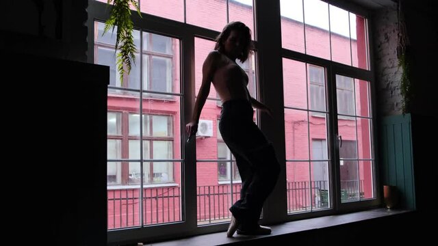 silhouette of a woman dancing on the background of a large window.