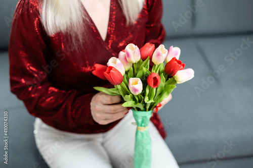 Young woman at home mother's day concept holding tulips bouquet smiling close-up
