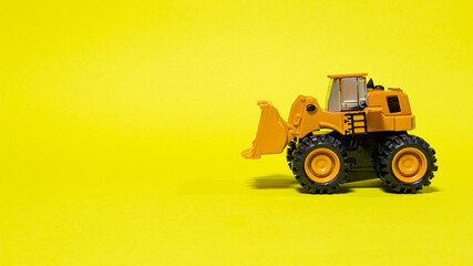 Toy typewriter tractor bulldozer on a yellow background. Toy for children