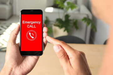 Hotline service. Man making emergency call via smartphone indoors, closeup