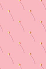 Toothbrushes with yellow bristles on a pink background. Pattern. Oral hygiene, dentistry, teeth cleaning concept. Minimalism, top view, copy space.