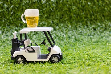 Golf cart with glass of beer on green grass background