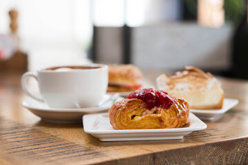 Puff pastry with berry filling on the background of buns and a cup of coffee. Morning composition on a wooden table. Serving breakfast