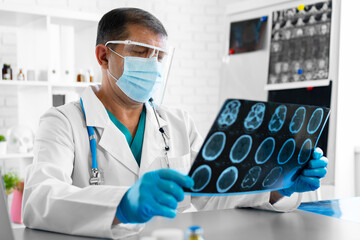Man doctor examining head mri while sitting at the table in hospital