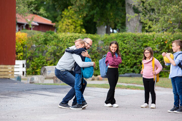 Father hugging son in front of school
