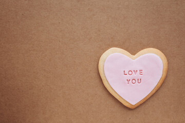 Obraz premium Heart shaped cookies with pink glaze and the inscription: «love you» located on a craft paper background with space for your text..Valentine's Day gifts