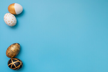 Golden, black, white easter eggs on blue background. Geometry. Minimal easter concept. View from above. Easter card with copy space for text.