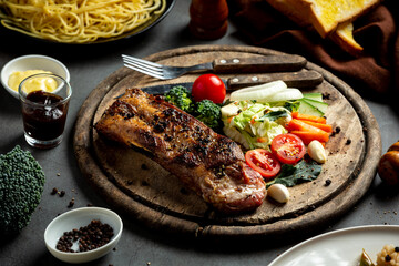 Roasted pork steak and vegetables on wooden cutting board